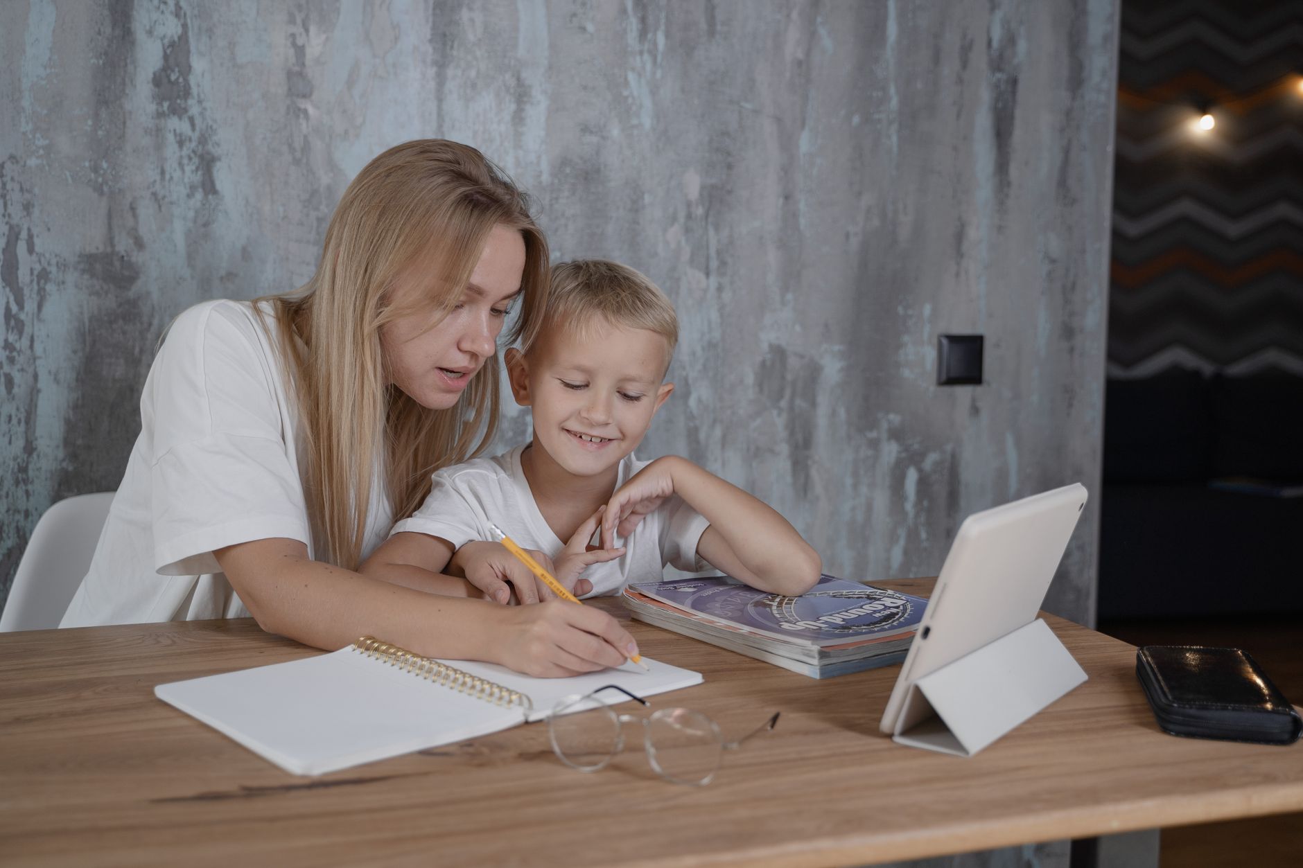 A parent helping a child work through a written daily plan at the kitchen table