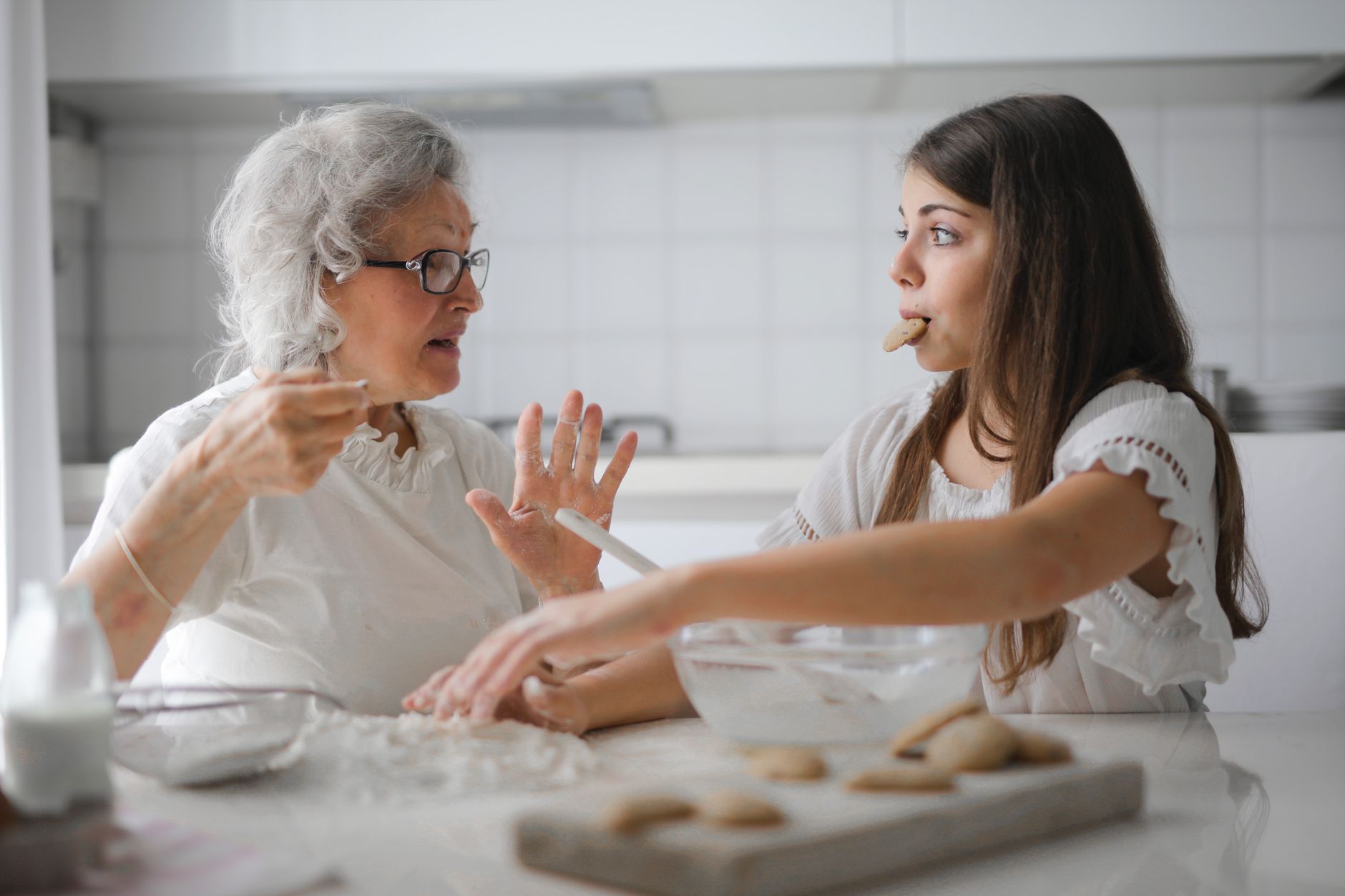A grandmother and grandchild baking together in a bright kitchen, sharing the same routine