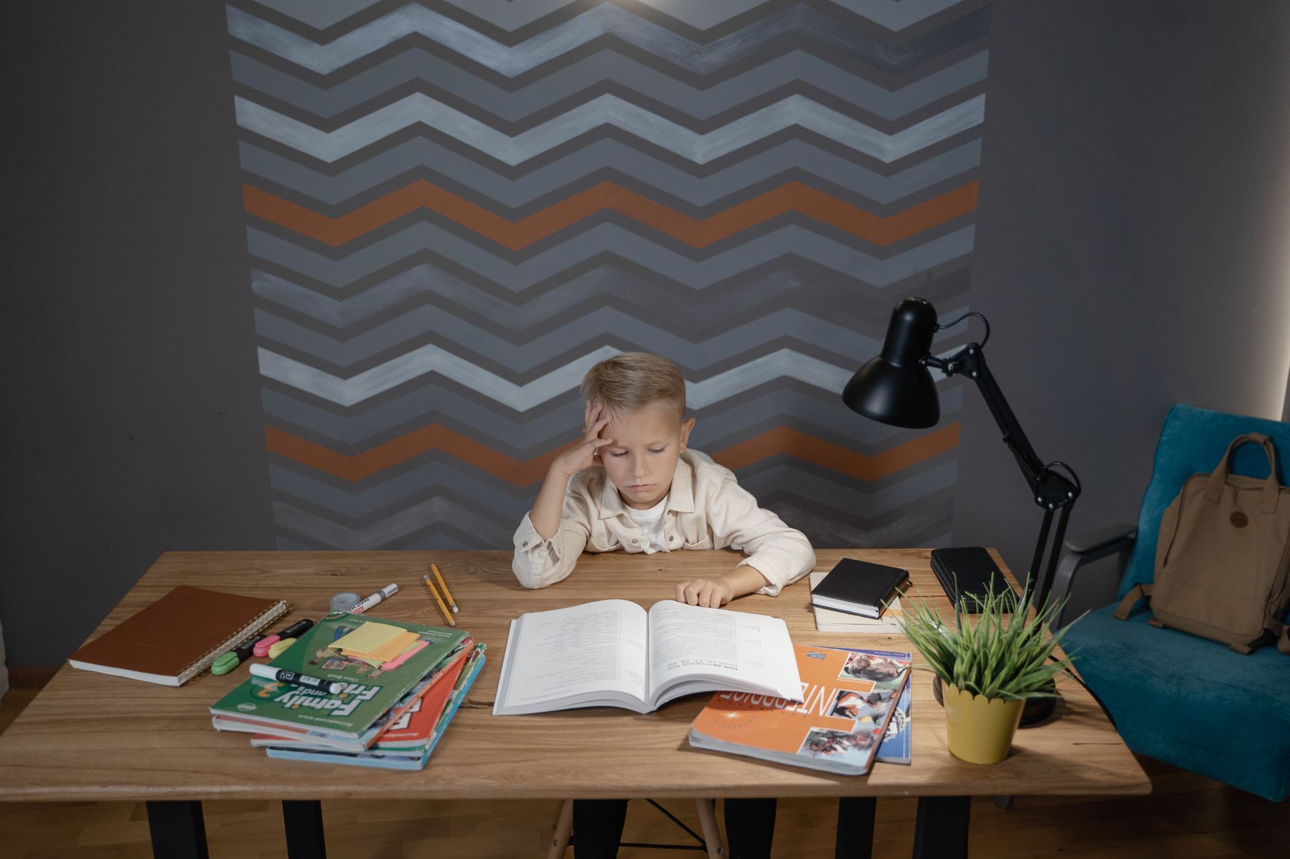 A child at a desk with an open book and school supplies, following a visible plan
