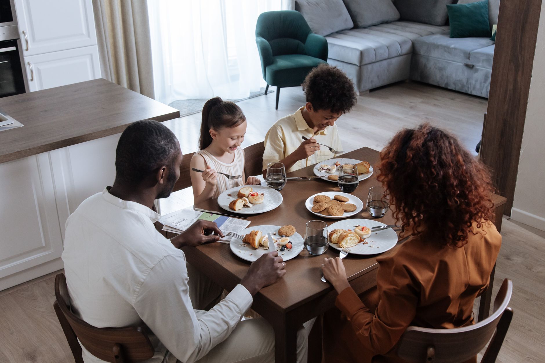 Parents and two children sharing a meal and a weekly family plan at the kitchen table
