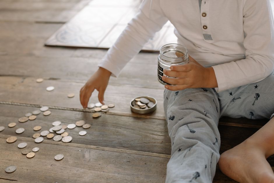 A child counting coins into a savings jar