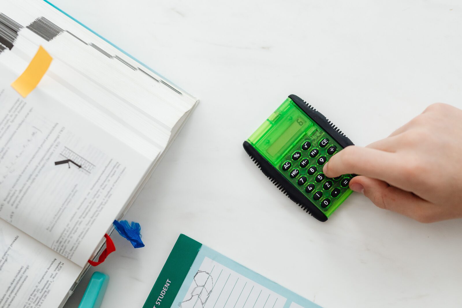A student working out practice problems with a calculator and textbook