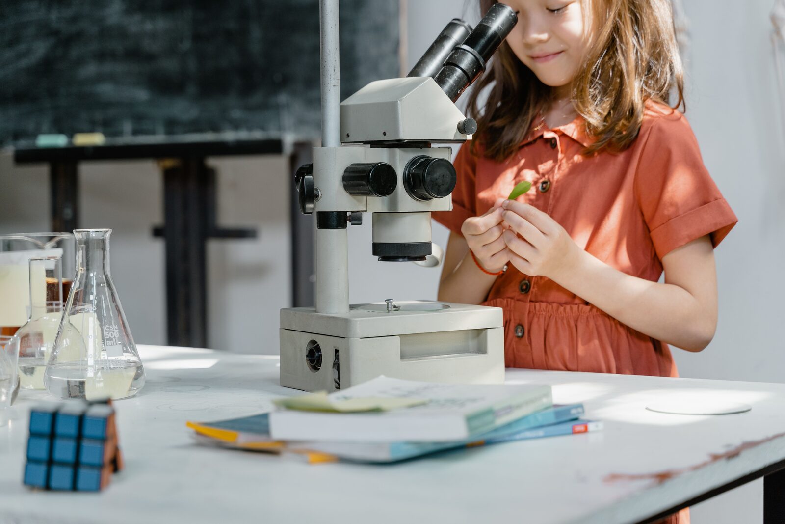 A girl looking through a microscope at a classroom science table