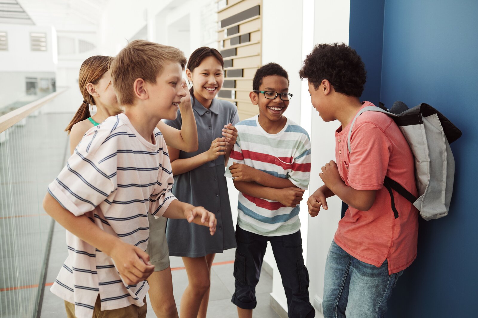 Middle schoolers laughing together in a bright school hallway
