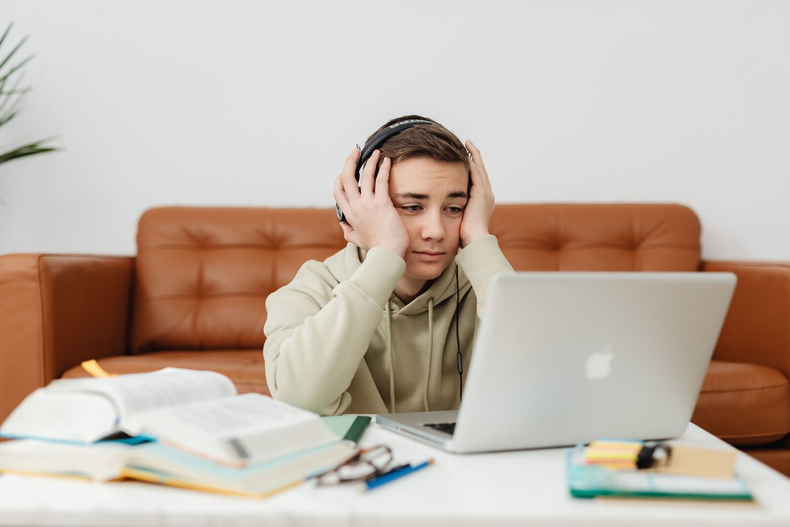 A middle schooler with headphones pausing over a laptop during a long practice session