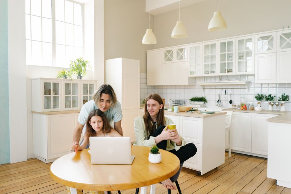 A family planning the week together on a phone and laptop at the kitchen table